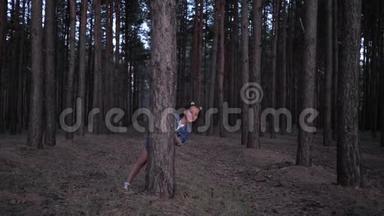 户外游戏，小女孩从树后面窥视，然后在森林中的一排排松树之间奔跑，周末晚上